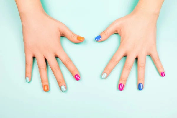 Frauenhände mit Maniküre in trendigen Neonfarben auf türkisfarbenem b — Stockfoto