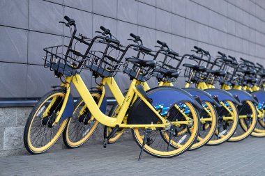 Duvarın yanında kiralık şehir bisikletleri var.