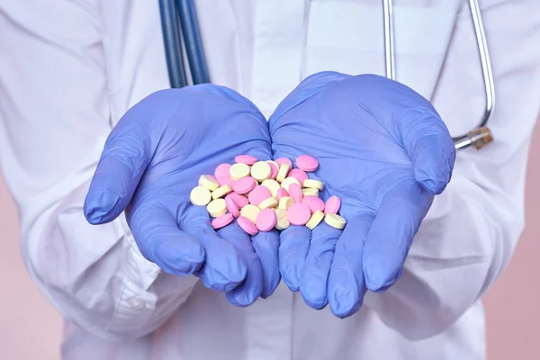 Lastik eldivenli doktor bir avuç dolusu hap tutuyor. Tıbbi konsept