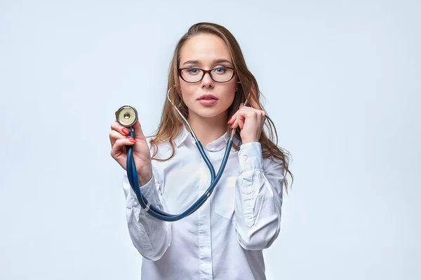 Gözlüklü genç çekici doktor steteskop kullanarak nefes alışını dinliyor. Tıbbi konsept.