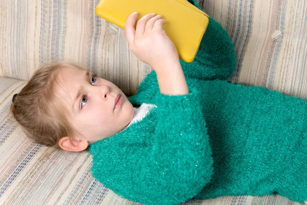 Jeune fille lecture tablette sur le canapé — Photo