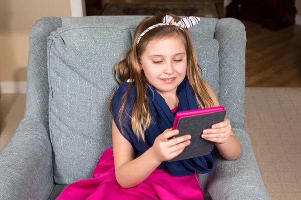 Fille dans une chaise lecture d'une tablette — Photo