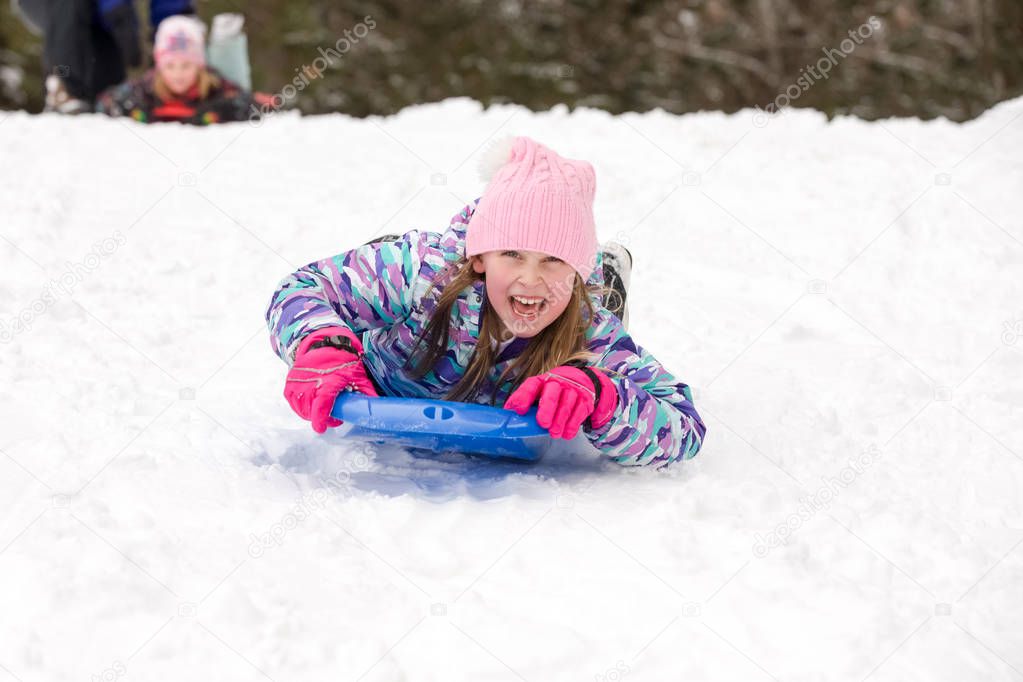 Girl Sledding Head First and Looking at Camera
