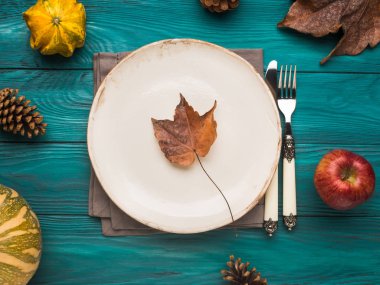 Boş tabak kabak ve sarı yaprakları ile Moody yeşil sonbahar arka plan üzerinde. Gıda natürmort düz yatıyordu düşme. Kopyalama alanı çerçeve