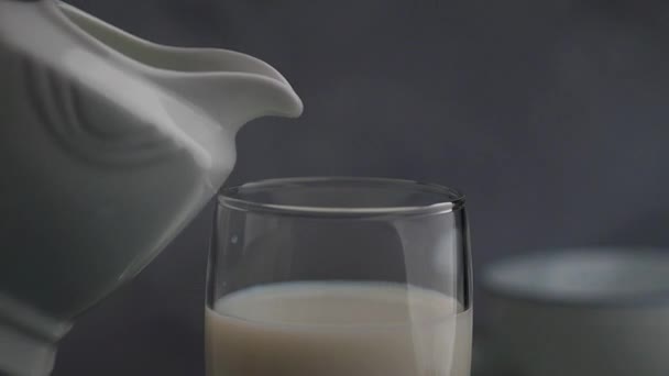 Pouring milk from a pitcher in a glass — Stock Video