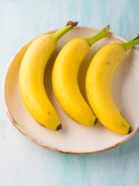 Banane in un piatto su sfondo verde pastello — Foto Stock