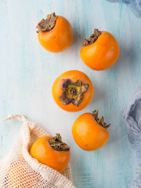 Ripe persimmons on turquoise background — Stock Photo, Image