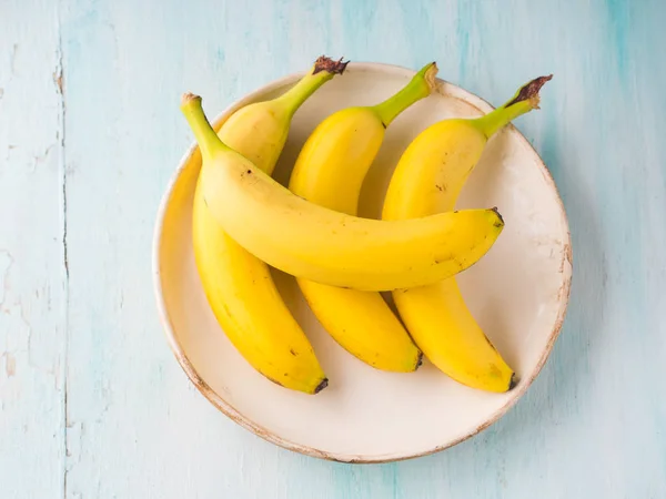 Banane in un piatto su sfondo verde pastello — Foto Stock