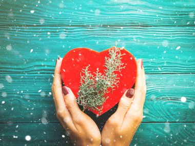 Kırmızı kalp hediye kutusu ve kadının el ile kar pul