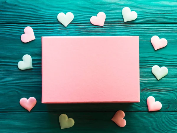 Рожева подарункова коробка на дерев'яному фоні з сердечками — стокове фото