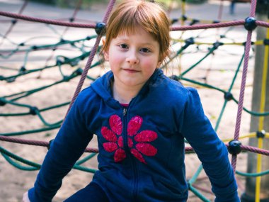 Oyun parkında oynayan küçük kızıl saçlı kız