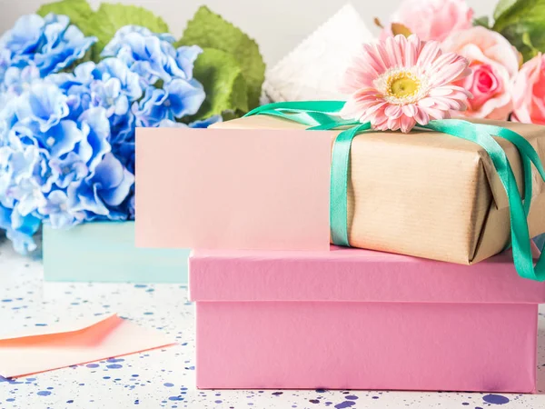 Tarjeta rosa en blanco y cajas de regalo apiladas. Flores — Foto de Stock