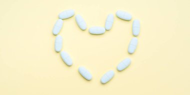 Kalp şekli üzerine pastel sarı oluşturan mavi haplar