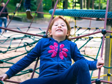 Oyun parkında oynayan küçük kızıl saçlı kız