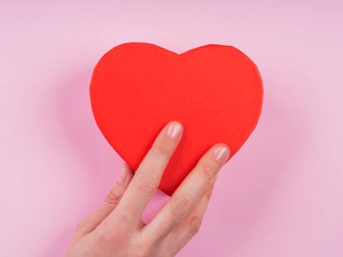 Pembe zemin üzerinde kırmızı kalp hediye kutusu