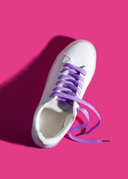 White sneaker with purple laces on pink