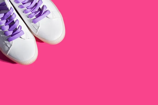 White sneakers with purple laces on bold pink