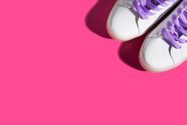 White sneakers with purple laces on bold pink