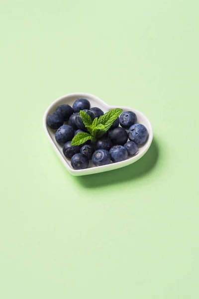 Heart of fresh blueberries on pastel green — Stock Photo, Image