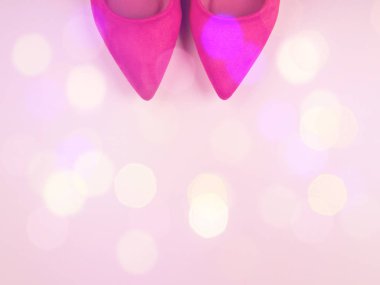 Kadın pompaları ve şenlikli ışıklar ile pembe arka plan