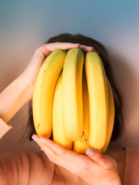 Ragazza che copre il viso con mazzo di banane — Foto Stock