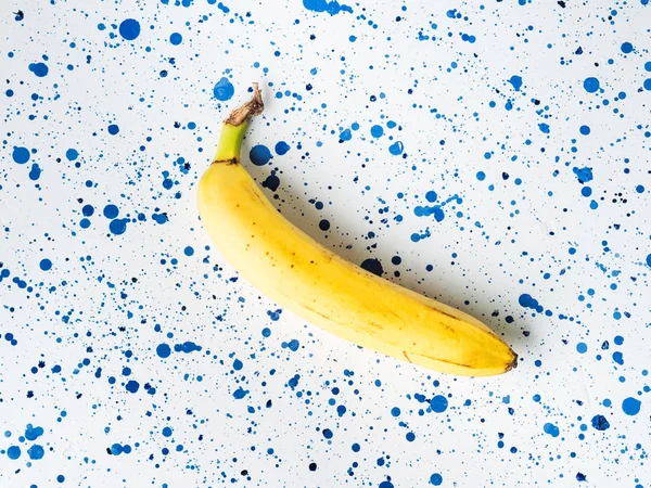 Una banana posa su sfondo bianco astratto — Foto Stock