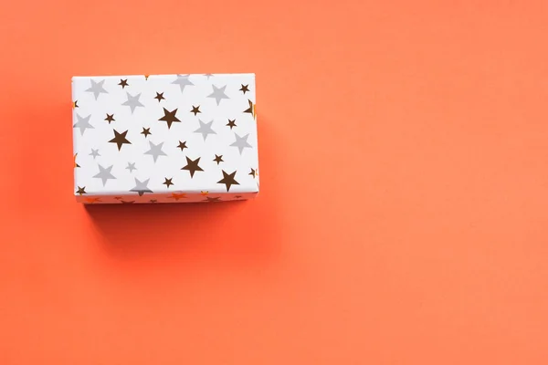 Белая коробка подарков со звездами на оранжевом коралле — стоковое фото
