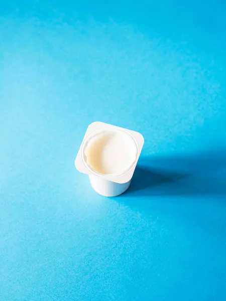 Plain yogurt in plastic glass on blue