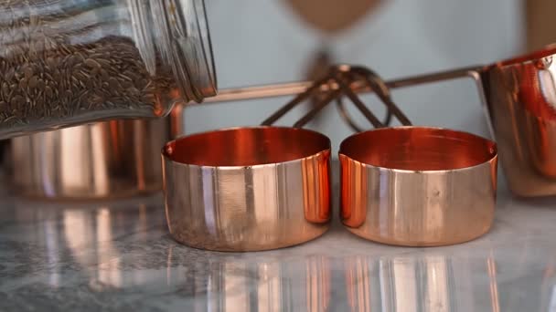 Copper cups on marble. Pouring flax seeds — Stock Video