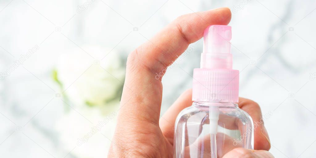 Womans hand spritzing liquid from spray