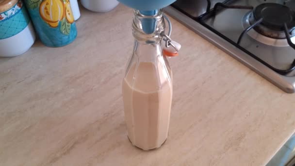 Pouring home made plant milk in a glass bottle — Stock Video