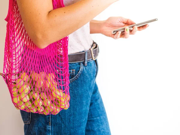 Woman with reusable mesh bag and smartphone