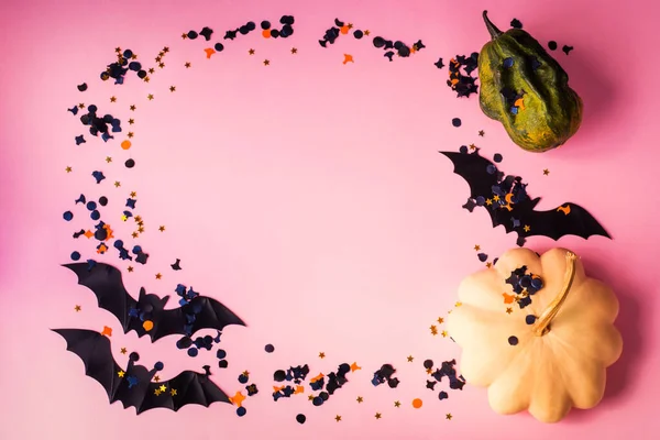 Halloween pumpkin and bat with confetti on pink