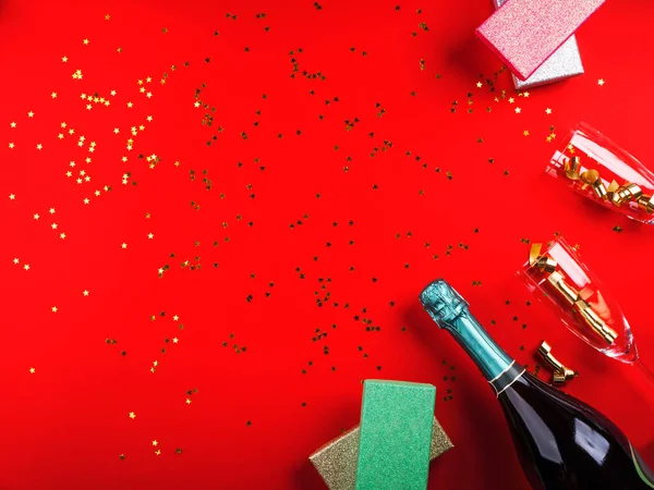 Champanhe, presentes e flauta em vermelho com confete — Fotografia de Stock