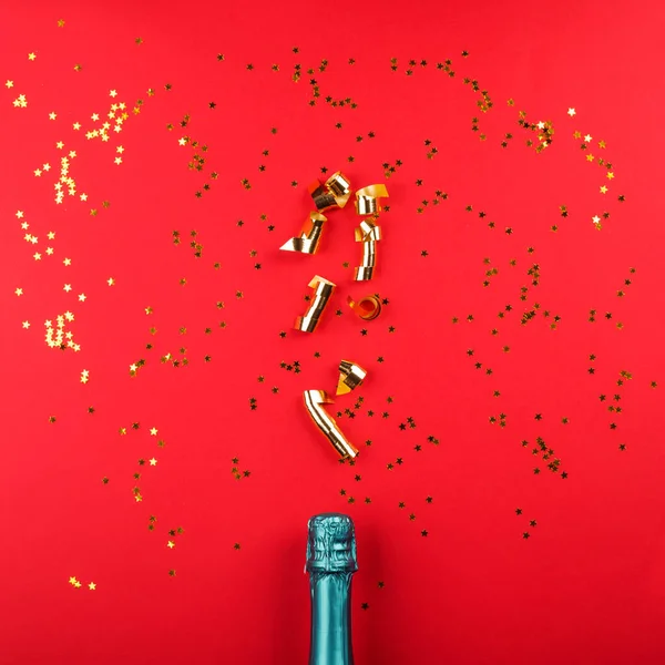 Garrafa de champanhe e fluxo de confete no vermelho — Fotografia de Stock