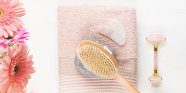 Masaj fırçası, taş, pembe havlu üzerinde yüz silindiri