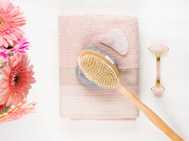 Masaj fırçası, taş, pembe havlu üzerinde yüz silindiri