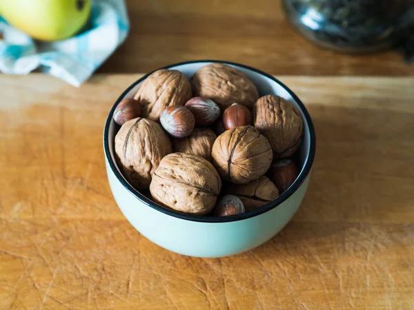 Walnuts and hazelnuts in green bowl — Stock Photo, Image