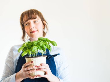 Genç kadın evde taze fesleğen yetiştiriyor.