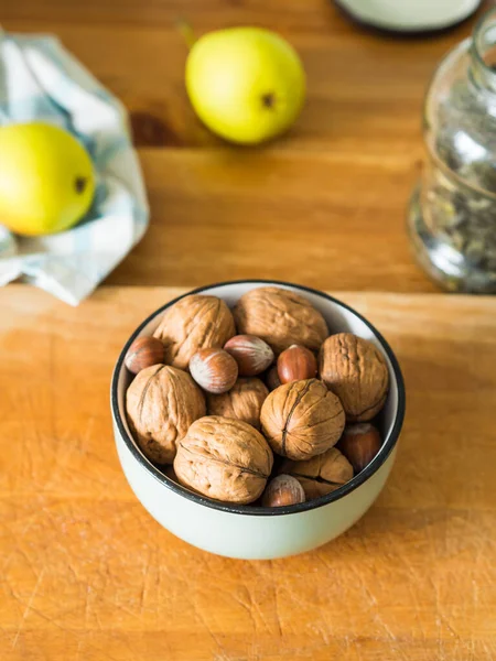 Walnuts and hazelnuts in bowl on wooden board. — Stock Photo, Image