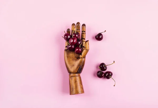 Eine Handvoll Kirschen in Holzhand auf rosa — Stockfoto