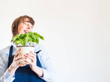 Genç kadın evde taze fesleğen yetiştiriyor.