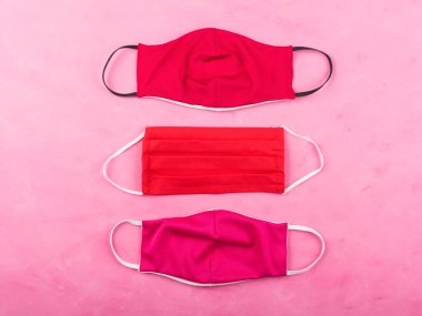 Pembe arka planda kırmızı maskeler. Coronavirüs