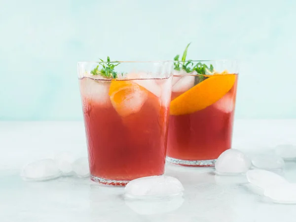 鮮やかなターコイズの背景に氷 ミントの葉とレモンとオレンジのスライスとガラスの新鮮な赤のカクテルモッキーサングリア — ストック写真