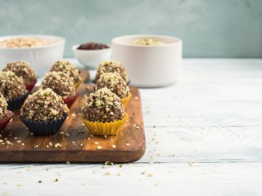 Ev yapımı, yulaf, fındık, hurma, kurutulmuş meyve, keten ve kenevir tohumu, çikolata parçaları ve tahta tahtada kağıt kutularda servis edilen akçaağaç şurubu içeren vegan enerji proteini topları. Boşluğu kopyala