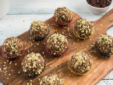 Yulaf, fındık, hurma, kurutulmuş meyve, keten ve kenevir tohumu, çikolata ucu ve akçaağaç şurubu içeren ev yapımı vegan enerji proteini topları tahta tahta tabakalarda servis ediliyor..