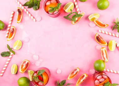 Yazın kullanılan malzemelerle pembe arka planda kan portakalı ve limonlu buzlu kırmızı kokteyl. Çerçeve, kopyala boşluk