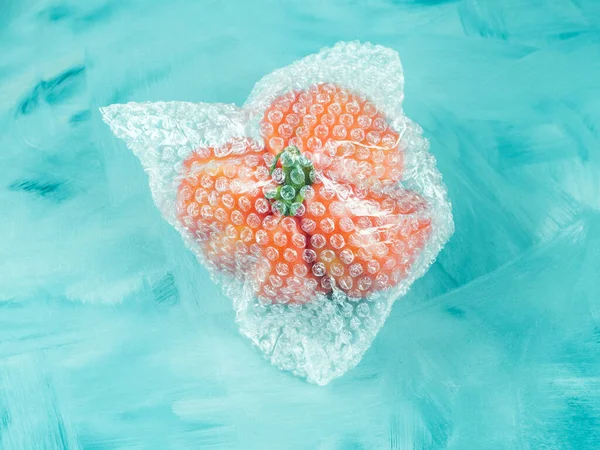 Tomate in Kunststoffverpackung auf Türkis — Stockfoto