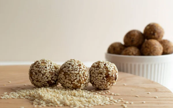 Homemade healthy vegan raw energy truffle balls in  sesame seeds on wooden board. Made with dried dates, walnuts, almonds and cashews in sesame seeds, matcha powder and carob. The concept of healthy and vegetarian food. Close-up