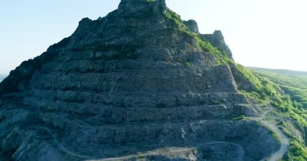 ドローンは山の近くの岩峰の周りを空中から眺め そこに石の山が示されています — ストック動画